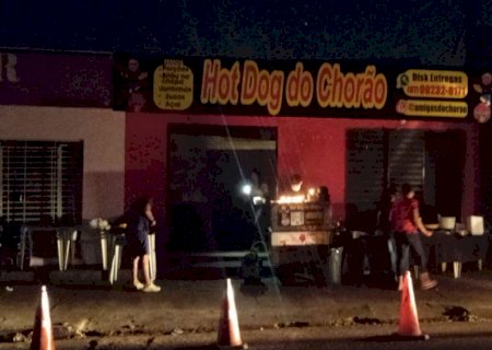 Bairro fica sem energia e empresário vende cachorro quente à luz de velas na calçada